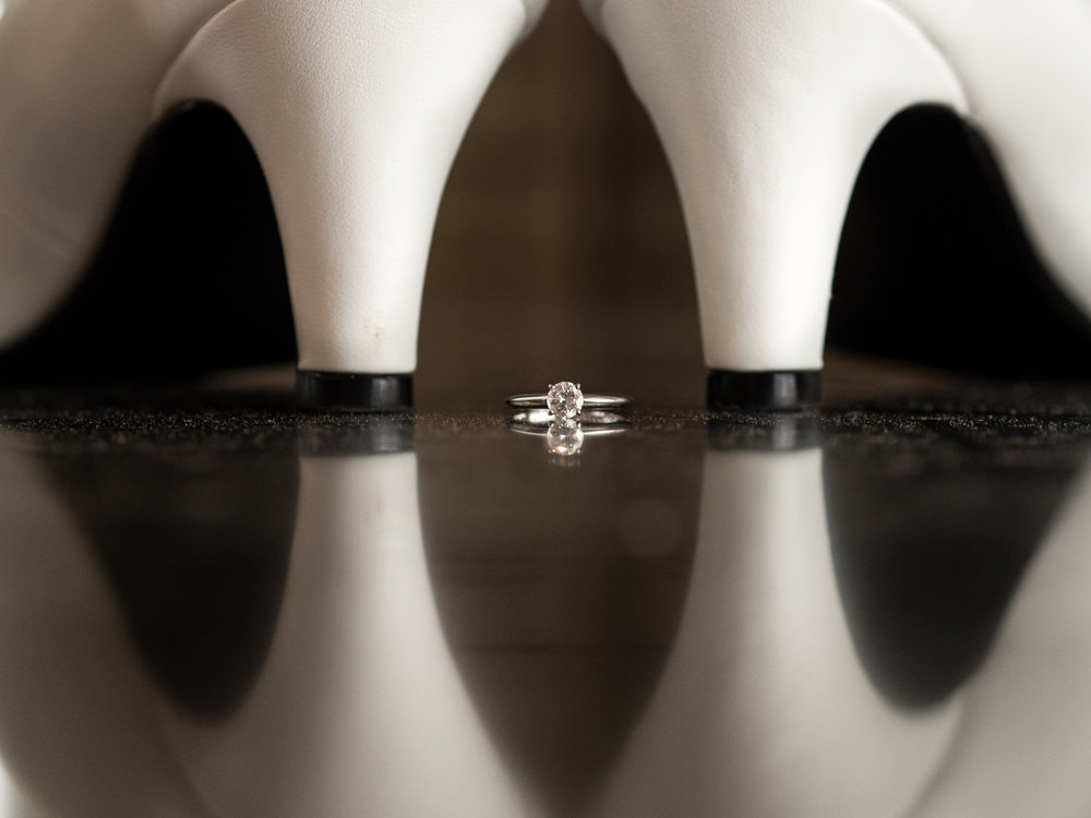 Bride's ring and wedding shoes on reflective surface