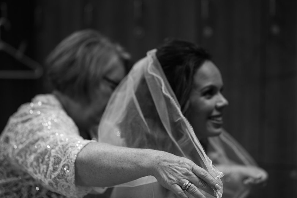 Mom helping bride with veil in Pilot Knob Country Club. Wedding Photography by Party of Two Photography.