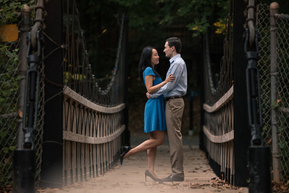 Cute engagement photo idea of standing on bridge in Freedom Park in Charlotte, North Carolina. Engagement Photography by Party of Two Photography.