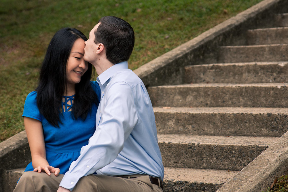 Sweet engagement photography of forehead kiss on stairs in Freedom Park in Charlotte, North Carolina. Engagement Photography by Party of Two Photography.