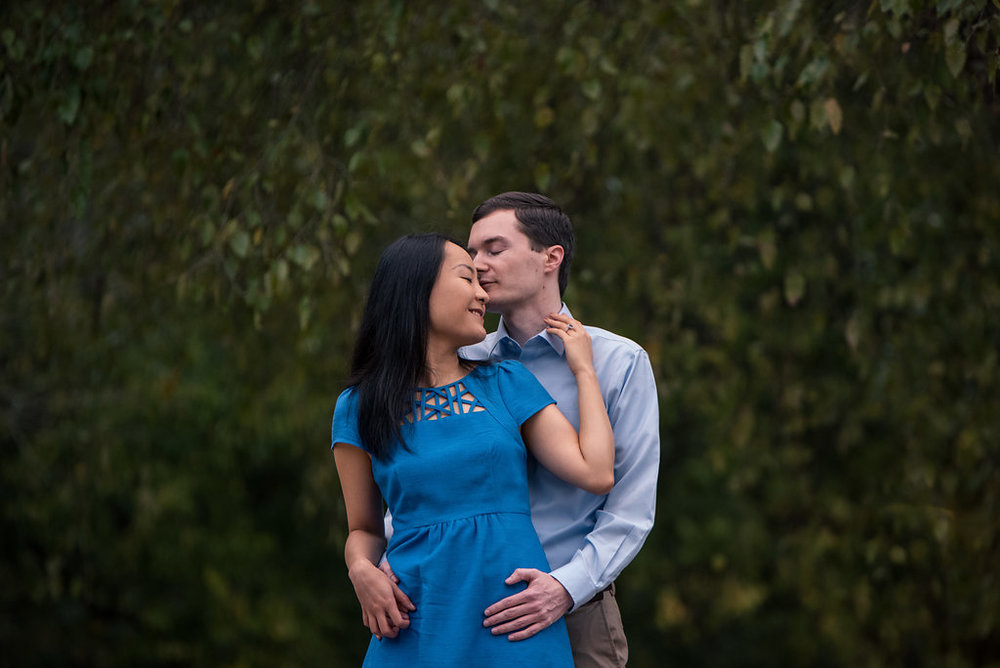 Couple holding each other in front of trees in Freedom Park in Charlotte, North Carolina. Engagement Photography by Party of Two Photography.