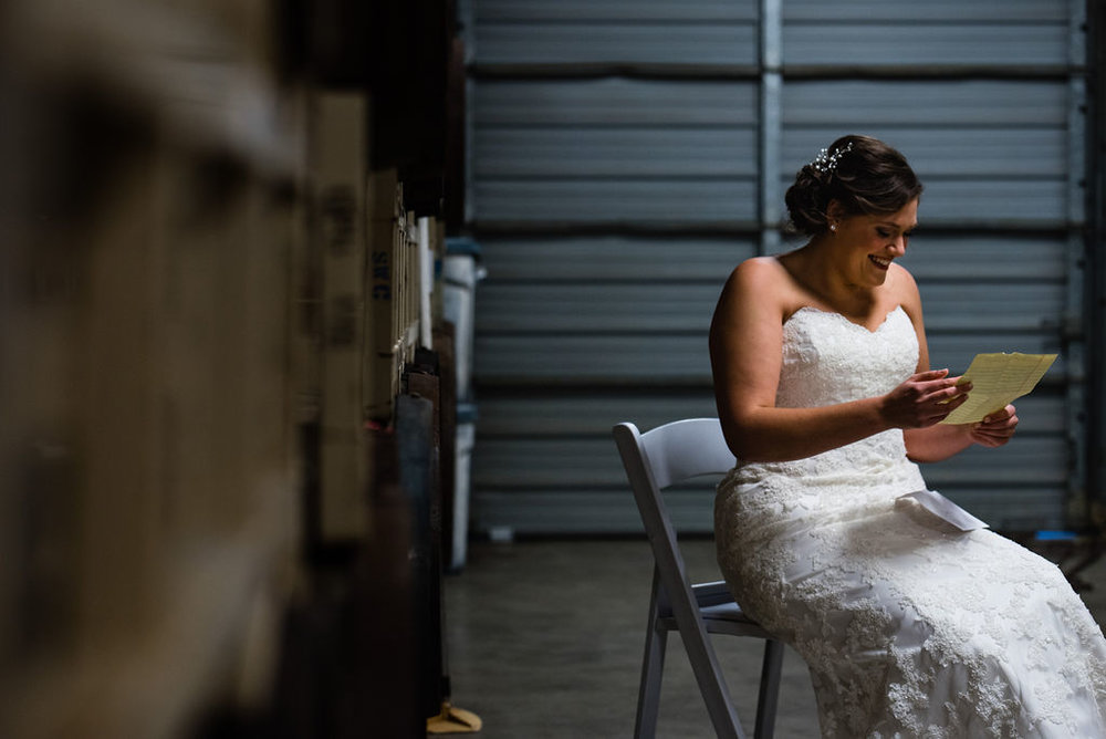 Bride Reading Letter at Triple C Barrel Room by Charlotte Wedding Photographers