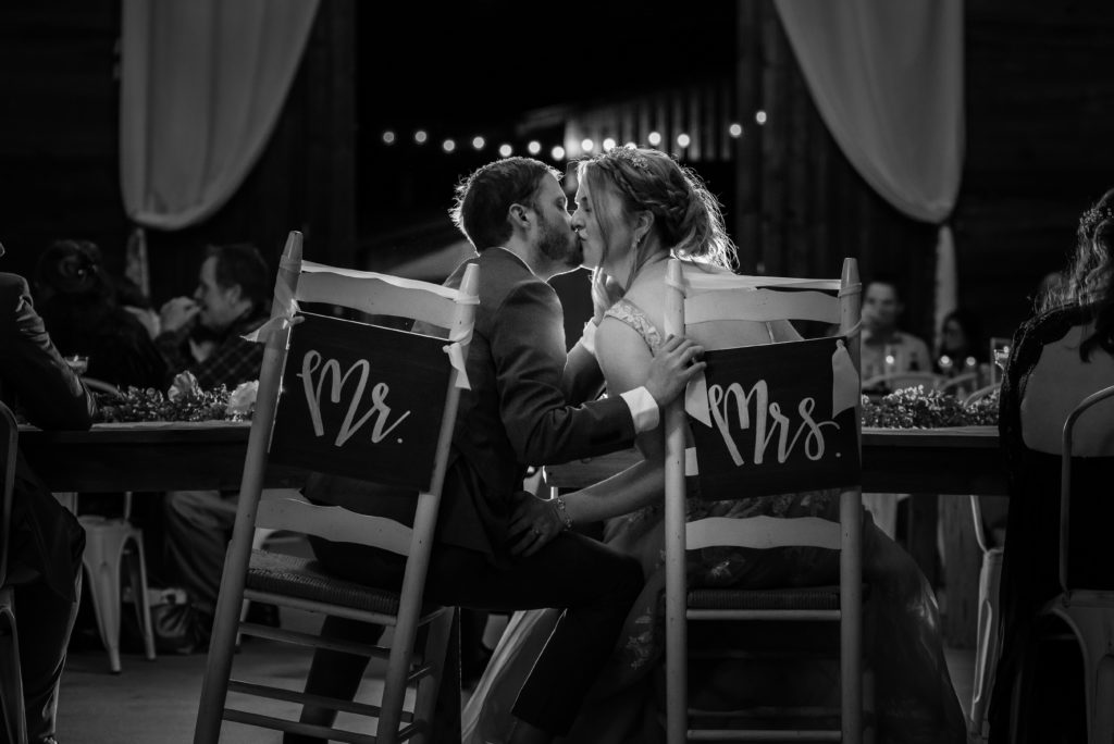 Black and White Newlyweds kissing at head table