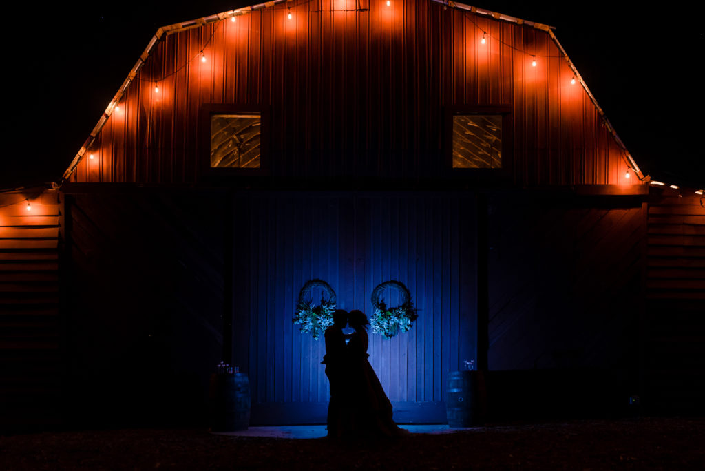 Creative wedding portrait of couple in front of 1932 barn