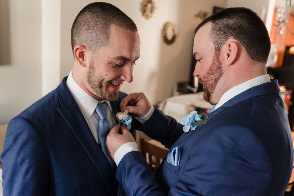 Groom getting dressed with blue suits