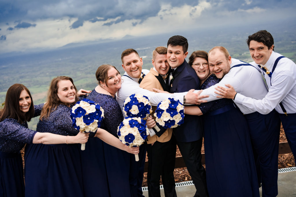 Fun wedding party poses with everyone hugging couple