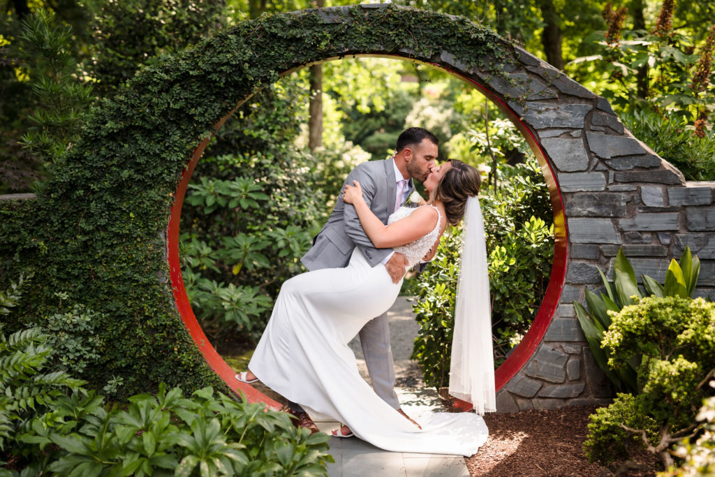 Interesting Japanese stone arch kiss and dip during UNCC Botanical Gardens Wedding Portraits