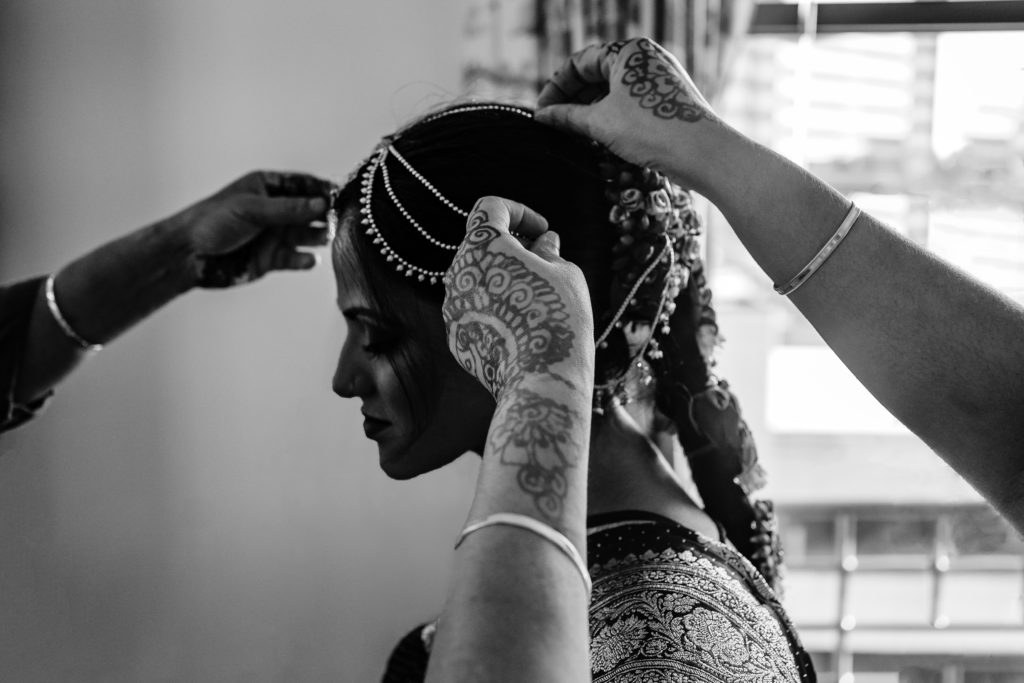 Family helping Indian bride get her hairpieces on.