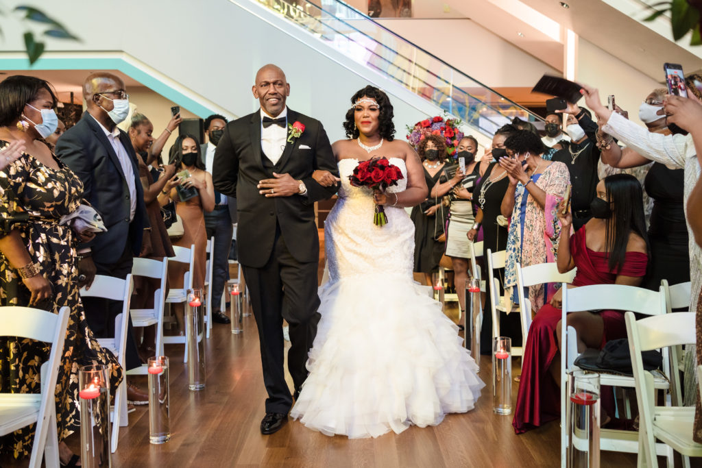 Bride and Father walk down aisle of Mint Museum before wedding.