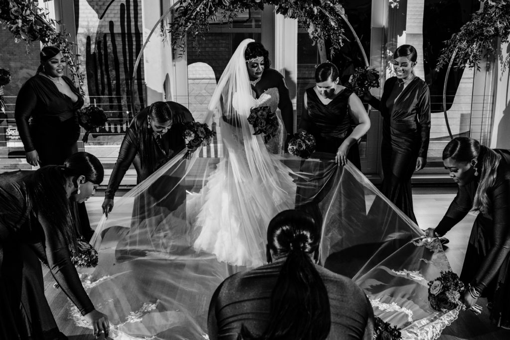 Bridesmaids help bride fan out her cathedral length veil