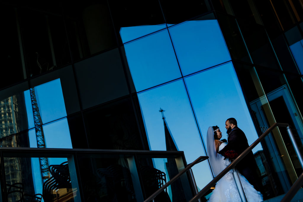 Wedding portrait of bride and groom at the Mint Museum with Uptown Charlotte in the background.