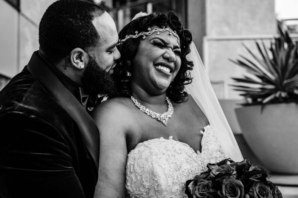 Laughing bride while groom is whispering into her ear