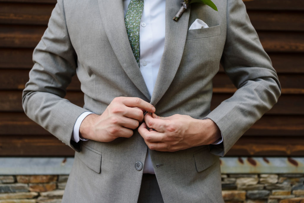 Groom buttoning final button of suit jacket at Alexander Homestead.
