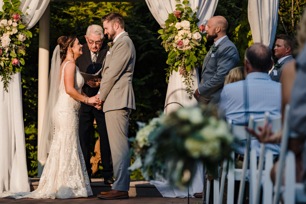 Megan and Mickey holding hands during their wedding ceremony at Alexander Homestead underneath the gazebo.