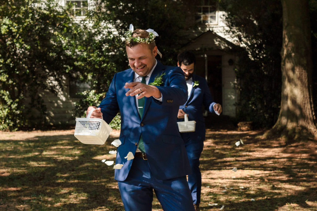 Flower gent spreading petals down the aisle in front of farm house