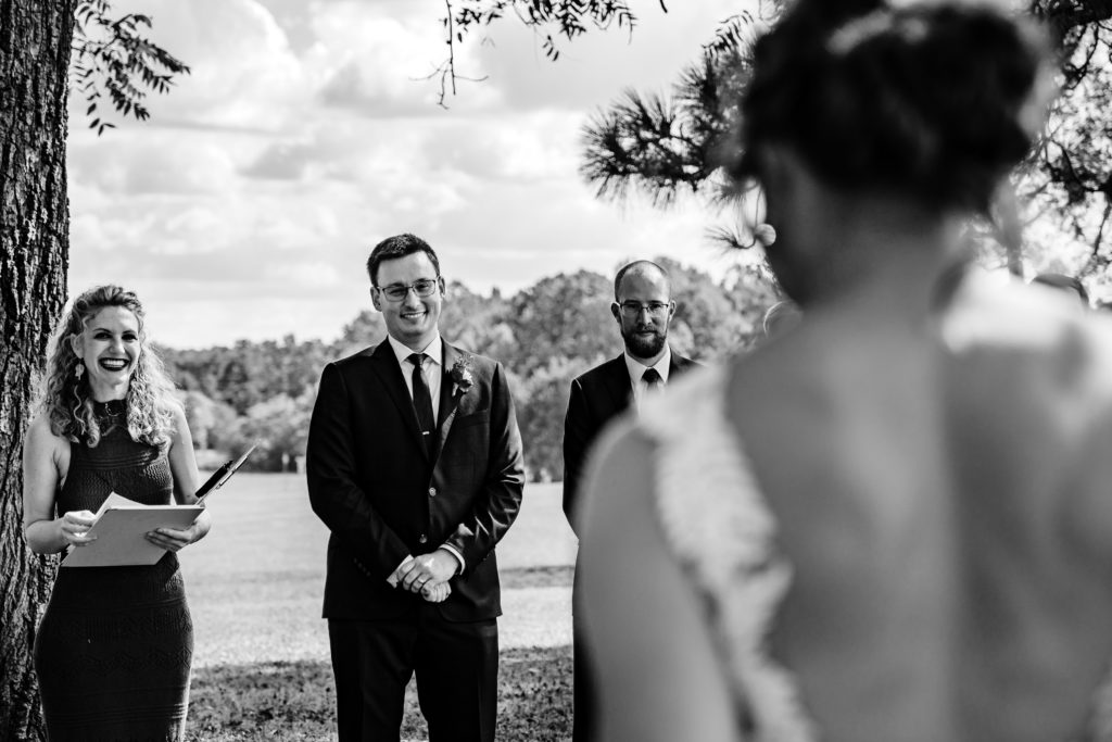 Groom reaction as he sees his bride for the first time while walking down the aisle in outdoor wedding ceremony on farm in North Carolina
