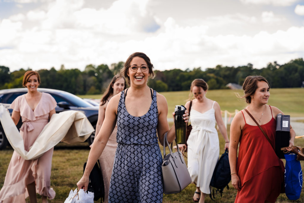 Bride and bridesmaids walking in field on north carolina farm to get dressed for wedding