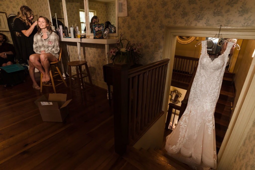 Bride getting makeup done with wedding dress hanging