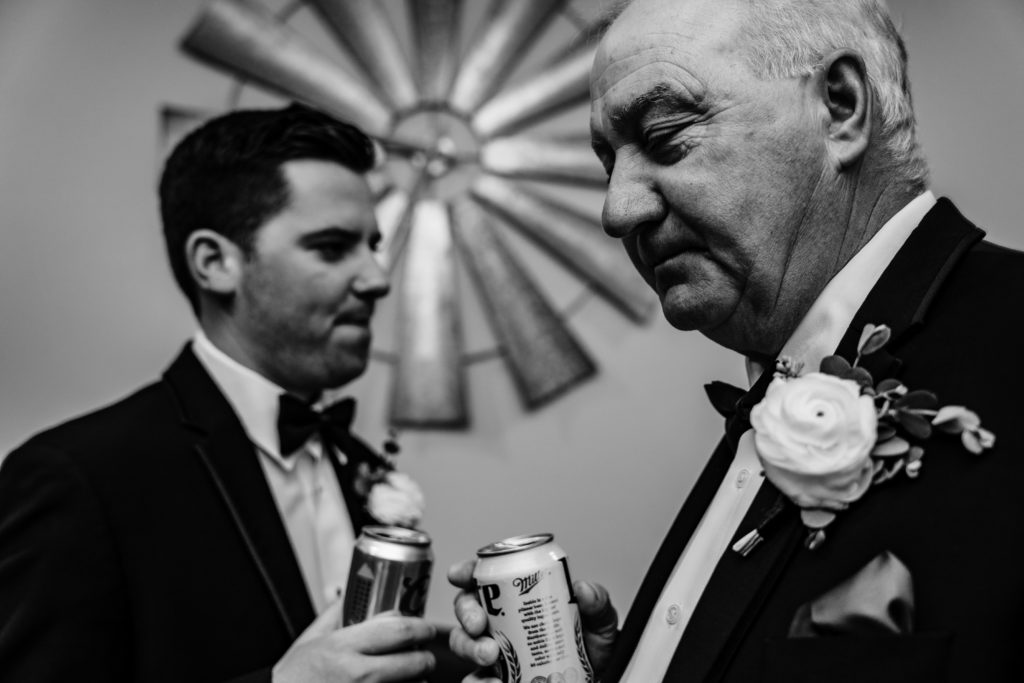 Groom and father share a beer before wedding
