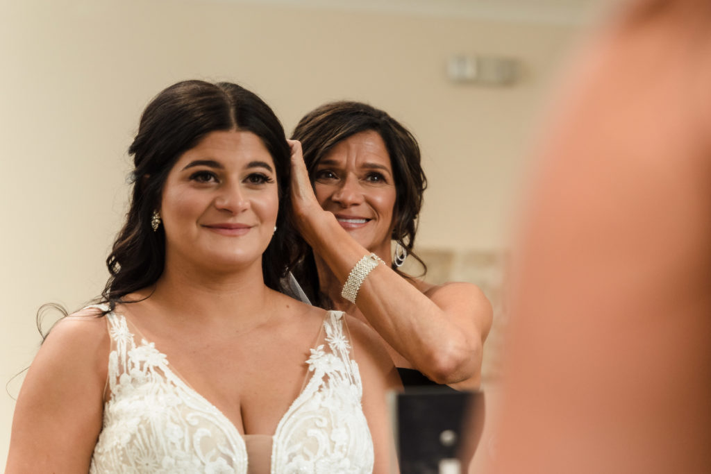 Mom smiles at bride in the mirror while adjusting her hair moments before her wedding at Sweet Magnolia Estate