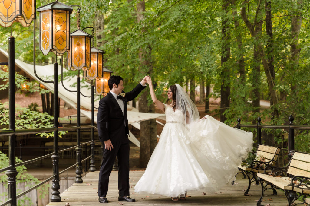 Groom twirling his bride on bridge during fall wedding reception at Castle McCulloch