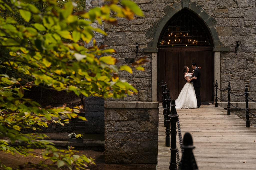 Fall wedding portrait of bride and groom against giant door at Castle McCulloch in Winston Salem