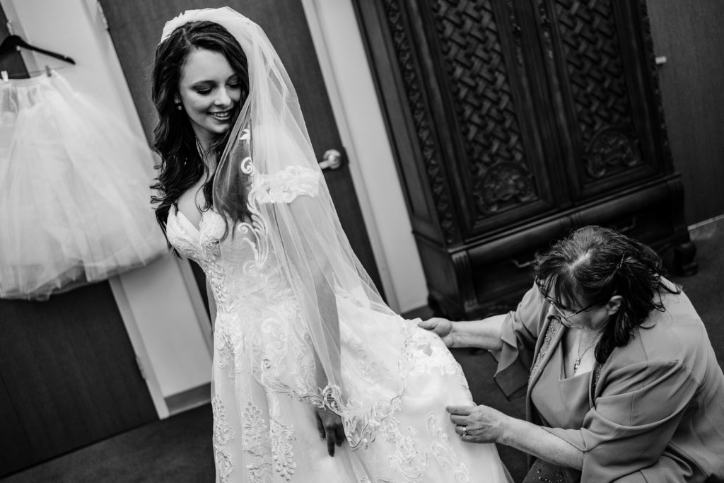 Bride with mother helping her check on dress before her catholic wedding ceremony in a Winston Salem church