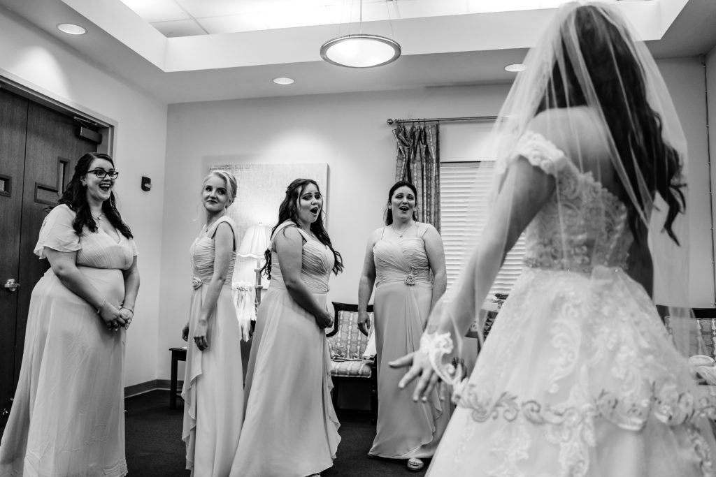 Bridesmaids see bride in wedding dress for the first time and react to her in a Catholic Winston Salem church