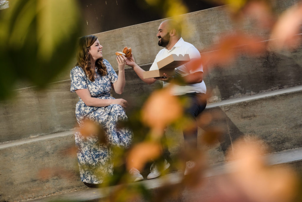 Couple cheersing donuts during engagement session