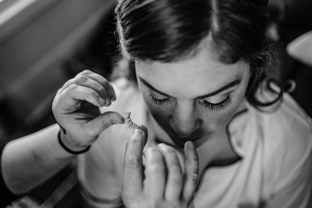 Bride gets fake eyelashes while getting ready for wedding at Venues at Langtree