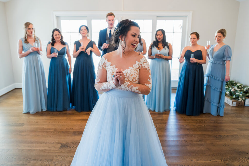 Bride showing off the back of her dress to her bridal party inside the home on the property of Pleasant Grove Farm before her wedding