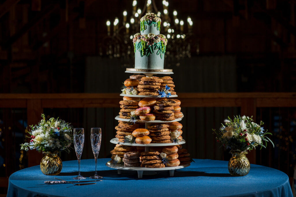 Wedding dessert tower on a blue table with homemade cake, cookies, and donuts