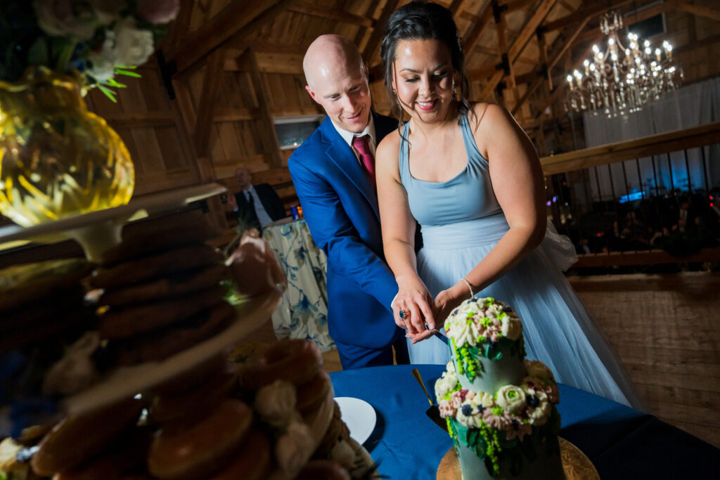 Bride and Groom cutting cake upstairs in barn wedding venue