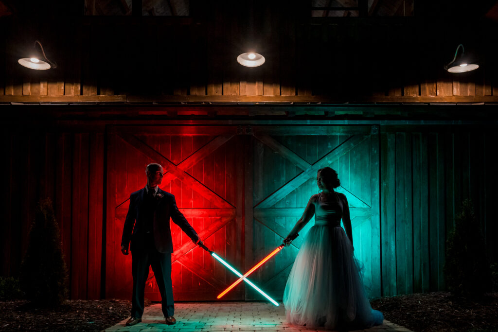 Cool and Nerdy night photography of wedding couple holding lightsabers together 