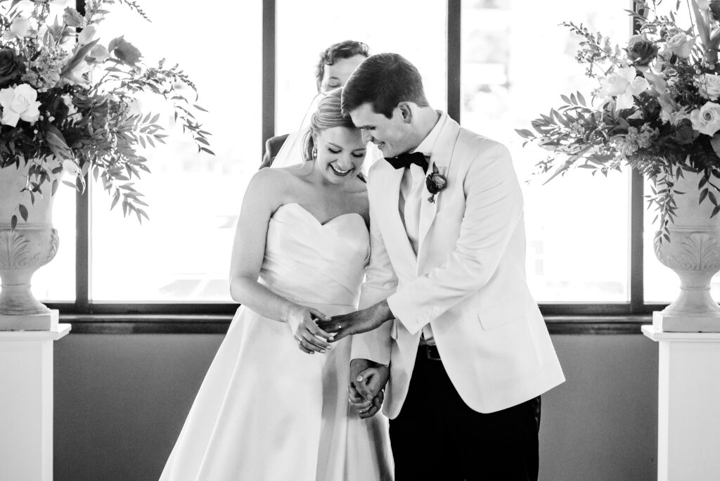 Bride and Groom look at wedding rings for their wedding surrounded by Spring flowers at Terrace at Cedar Hill Venue in Charlotte