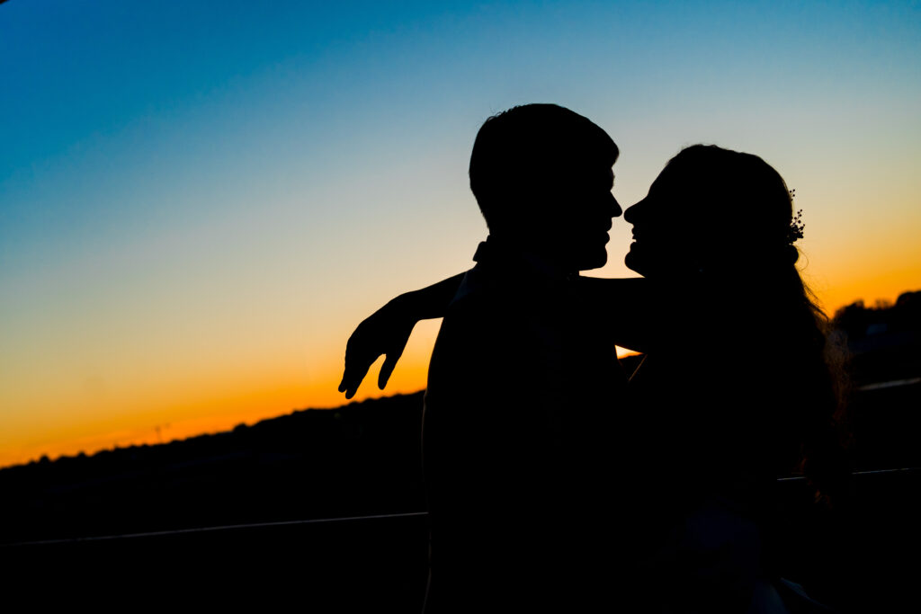 Bride and Groom are silhouetted against the sunset after their wedding ceremony during springtime at Terrace at Cedar Hill in Charlotte NC