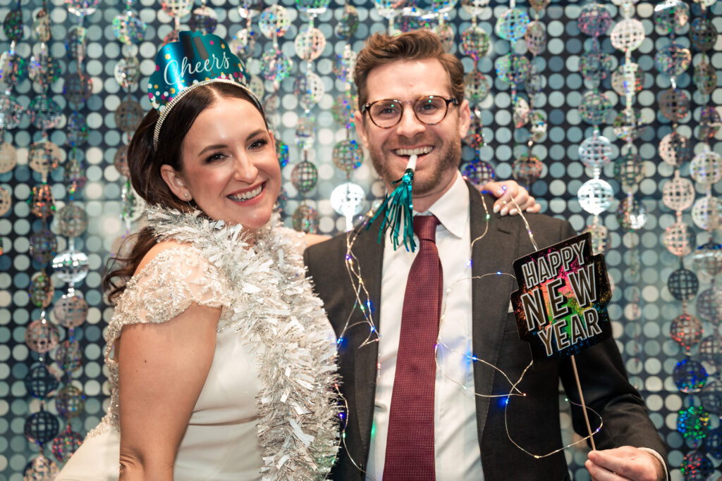 Bride and Groom posing with Happy New Years props to celebrate their wedding in Charlotte NC