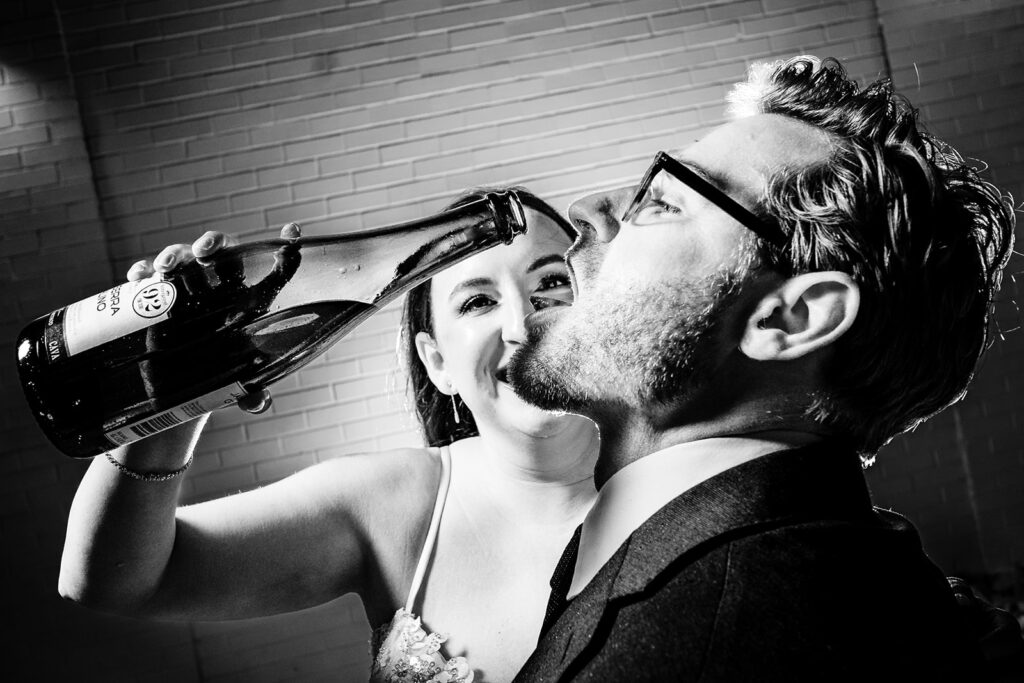 Funny wedding photography of Bride pouring champagne in Groom's mouth to celebrate New Years Eve in Charlotte